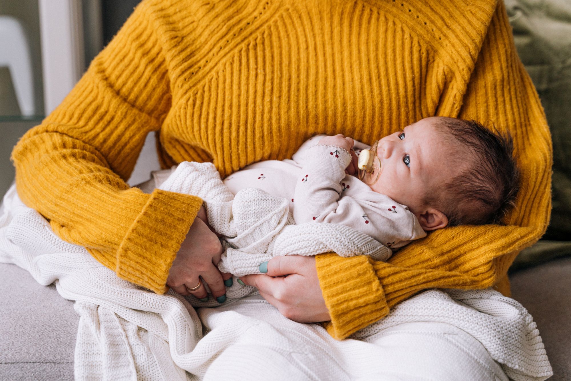 woman with a yellow sweater holding a baby to rock to sleep.