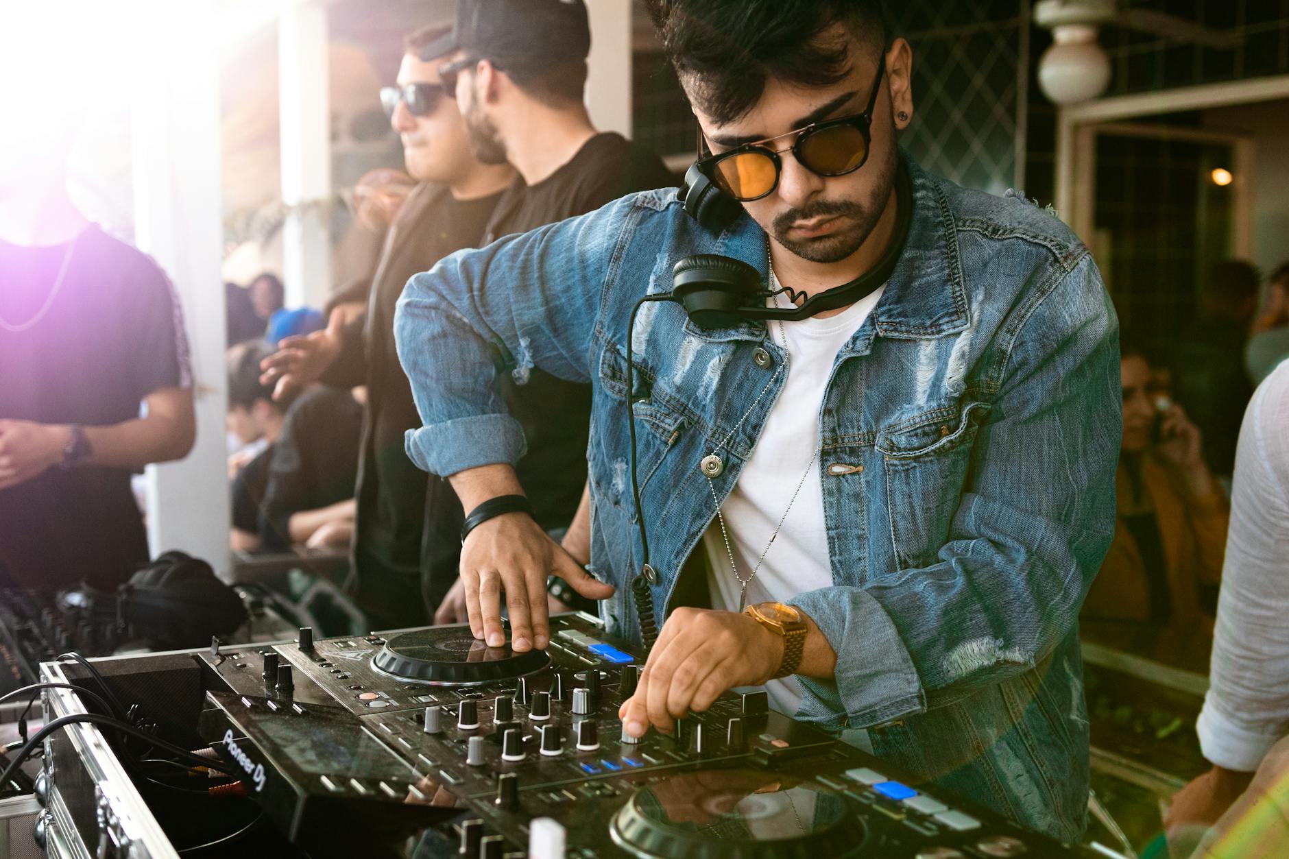 man wearing blue denim jacket while using black dj controller