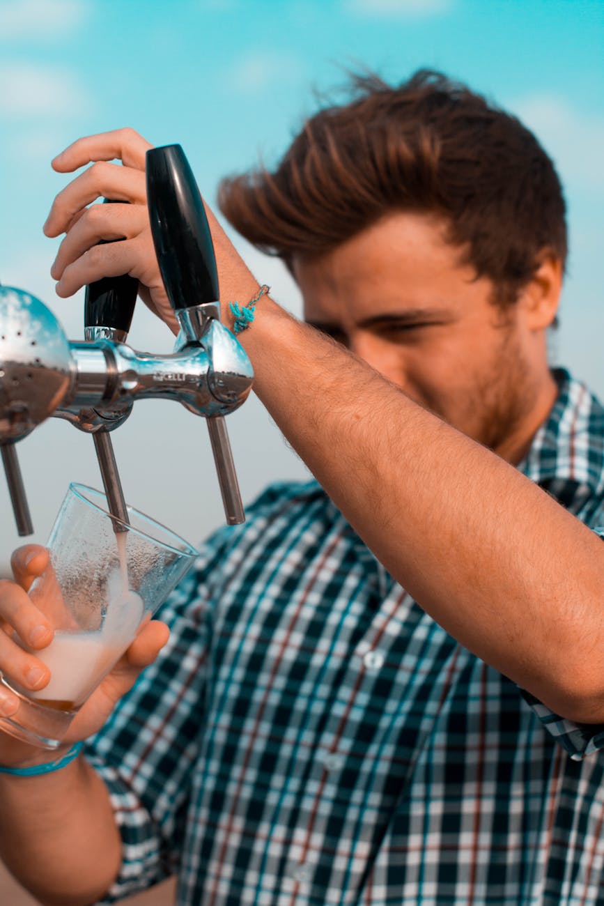 man holding black beer tap handle pouring beer on clear glass