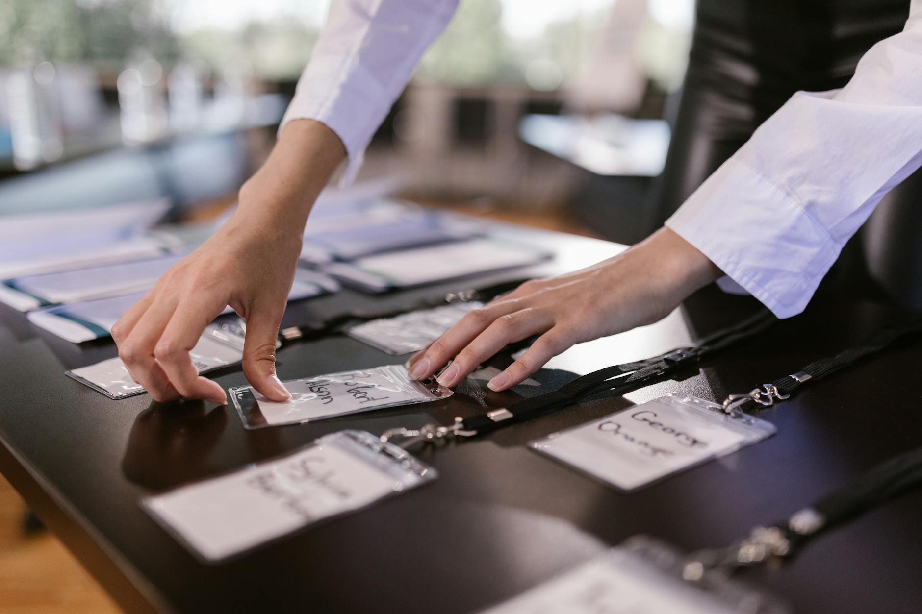 person arranging name tags with laces on a desk